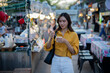 © Laingzaifa - Asian women enjoy delicious street food at night markets, smiling throughout their vacation, exploring the city's culture, vibrant lights, and fun-filled adventures.