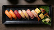 © MicroNL - Assorted nigiri sushi set on black plate with wasabi and pickled ginger, overhead view