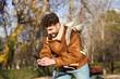 © Oscar - Young man using smartphone while cycling in urban park