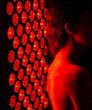 © Kirk Fisher - A healthy young woman stands in front of a red light therapy lamp.