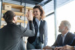 © opolja - Business colleagues celebrating success in a boardroom. Two happy business people doing a high five during a meeting in an office