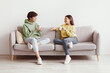 © Prostock-studio - Young Asian man and woman drinking coffee and talking while sitting on couch at home. Loving millennial couple enjoying coffee while having conversation, spending weekend together