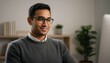 © shahinahmed - Smiling young man in glasses sitting at desk in modern office space with computer