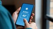 © The Little Hut - Man holds smartphone displaying sunny weather forecast with 40-degree temperature, illustrating modern technology