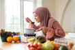 © Art_Photo - Happy asian muslim woman in hijab tasting hot soup with wooden ladle in kitchen at home, Islamic housewife cooking delicious halal food, Ramadan Iftar preparation and healthy nutrition concept