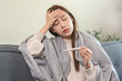 © Pormezz - Female sick woman checking her body temperature have a high fever feeling headache.