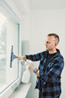 © DSMT - Man cleans window with spray bottle and squeegee in bright indoor setting during daytime