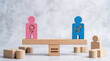© PURPLE VISION STUDIO - Pink female and blue male wooden figures standing perfectly on balance scale representing gender equality and fairness concept with harmony showing equal rights