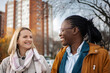 © Jelena - Two diverse adult women friends smiling and talking outdoors