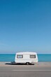© Andrii Zastrozhnov - Coastal serenity: white caravan by the sea under clear blue sky