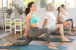 © JackF - Group of women in activewear doing stretching exercises during training yoga in modern sports club