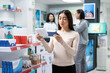 © DC Studio - Female customer carefully compares over the counter medicine while standing in drugstore aisle. Adult woman reads product labels and information to ensure she selects correct medication for her needs.