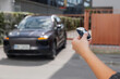 © 24K-Production - Woman stands holding a car key remote unlocking her parked car in an urban setting during daytime.