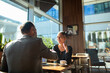 © Marko Geber - Two business people shaking hands in modern cafe meeting