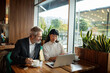 © Marko Geber - Two business colleagues discussing work on laptop in cafe