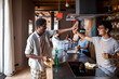 © Marko Geber - Roommates high-five while cleaning modern kitchen