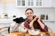 © New Africa - Woman making cookies near cute dog at wooden table in kitchen