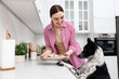 © New Africa - Woman with plate of bone shaped cookies near cute dog in kitchen