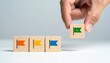 © pureart - 'Hand placing green flag block among row of four wooden blocks with colored flags and smiling faces, symbolizing selection and prioritization.'