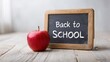 © Keo - A red apple next to a small chalkboard with the words 'Back to School' written on it.