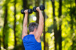 © Volodymyr - Mature man lifts a dumbbells during a morning fitness. Healthy senior trains with dumbbells. Sport in nature. Outdoor gym. Man exercises with dumbbells. 40s athlete training with dumbbells.
