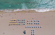 © Volodymyr - Beach aerial view on summer coast. Beach top view with umbrellas on sand. Beach shoreline in turquoise ocean. Beach vacation scene for travel.