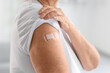 © Pixel-Shot - Senior woman with medical patch after vaccination at home, closeup