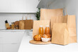 © Pixel-Shot - Paper bags with juice and pastry on counter in kitchen. Food delivery service