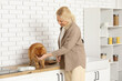 © Pixel-Shot - Mature woman feeding cute Pomeranian dog on counter in kitchen