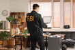 © Pixel-Shot - Male FBI agent with laptop in office, back view
