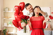 © Pixel-Shot - Young man with roses covering his wife's eyes at home on Valentine's Day