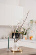 © Pixel-Shot - Vase with tree branches and Easter eggs on dining table in light kitchen