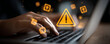 © Hathairat - Cyber security warning icon alert on laptop data risk online protection concept shows digital safety concern