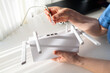 © kazakova0684 - Close-up of Woman Hands Plugging Ethernet RJ45 Cable into White WiFi Router on Desk