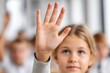 © whitestorm - A young blonde girl raising her hand in a classroom full of students, showing participation in a lesson, engaging in an educational setting with focus and determination.
