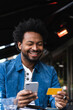 © Westend61 - Smiling man using credit card and smart phone for paying at sidewalk cafe