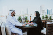 © oneinchpunch - Happy couple spending time in Dubai. man and woman wearing traditional clothes having a conversation in a cafe