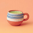 © virkusio - Handmade ceramic mug with speckled stripes filled with matcha latte on pastel peach background, minimalist drink still life with copy space