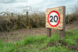 © Nick Beer - Shallow focus of a ground level 20MPH sign seen along a rural road in Britain. The road is on a nature reserve and is filled with potholes so advising drivers to drive slowly.