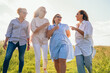 © Soloviova Liudmyla - Cheerful diverse women holding hand in hand walking through green grass meadow for woman friendship and happiness concept featuring four beautiful friends smiling in nature outdoor portrait area