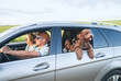 © Soloviova Liudmyla - Happy family with maltipoo dog traveling in silver car during summer road trip holiday vacation featuring man woman and child looking forward in outdoor nature meadow background area for journey
