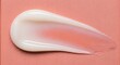 © Pratondo - Smooth white cosmetic cream or lotion swatch on soft peach pink textured background macro