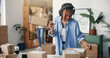 © peopleimages.com - Boxes, headphones and woman in office, startup for ecommerce and app for radio. Person, cardboard and entrepreneur in workplace, sound and listening to music, audio and checking for product barcode