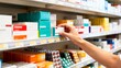 © Sakateka - Hand selecting medication from a pharmacy shelf