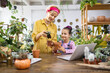 © sofiko14 - A woman and a young girl enjoy a gardening activity, repotting a plant in a cozy indoor setting