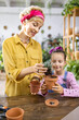 © sofiko14 - A woman and a young girl are focused on repotting a small succulent plant, enjoying a fun activity together