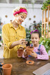 © sofiko14 - A woman and a young girl are enjoying a gardening activity together, repotting a small succulent plant