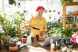 © sofiko14 - A woman in a yellow shirt is planting a succulent in a terracotta pot, enjoying the process