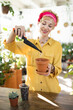 © sofiko14 - A smiling woman carefully adds soil to a small terracotta pot, preparing to plant a succulent