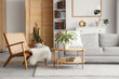 © Pixel-Shot - Bookcase, cozy sofa, coffee table and wicker armchair in interior of stylish living room. Blurred view